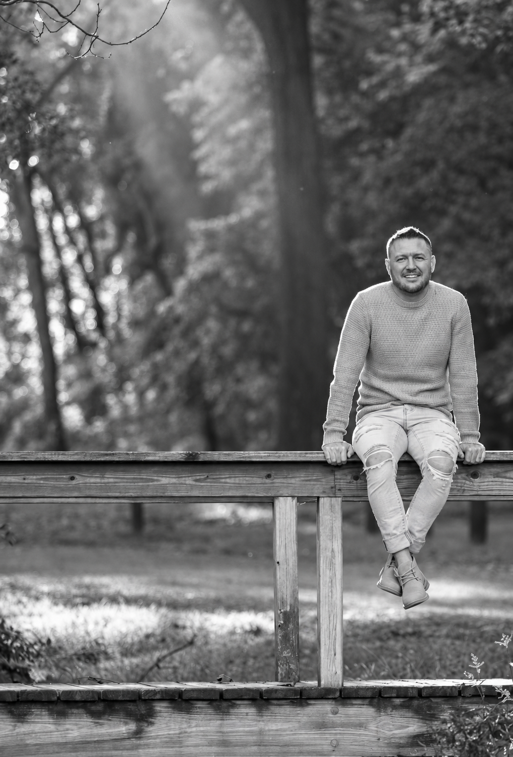 Brendon McGhee sitting on a wooden railing outdoors